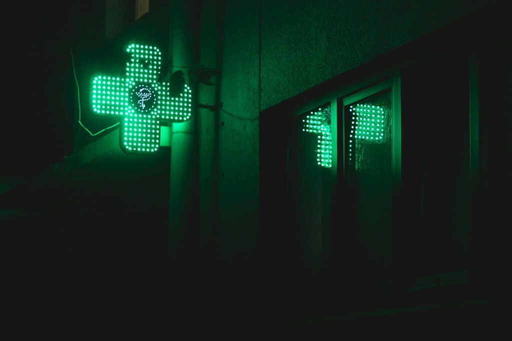 photo d'une pharmacie dans le noir avec la croix verte qui s'illumine
