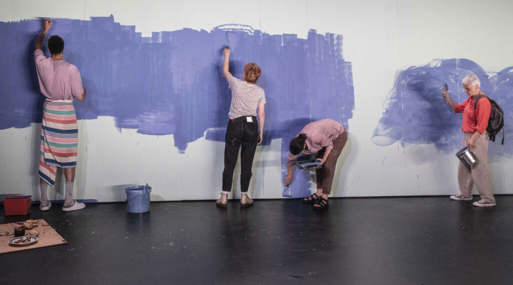 Acteurs peignant sur un mur pour le spectacle de théâtre contemporain Dialogue avec ce qui se passe à Paris.